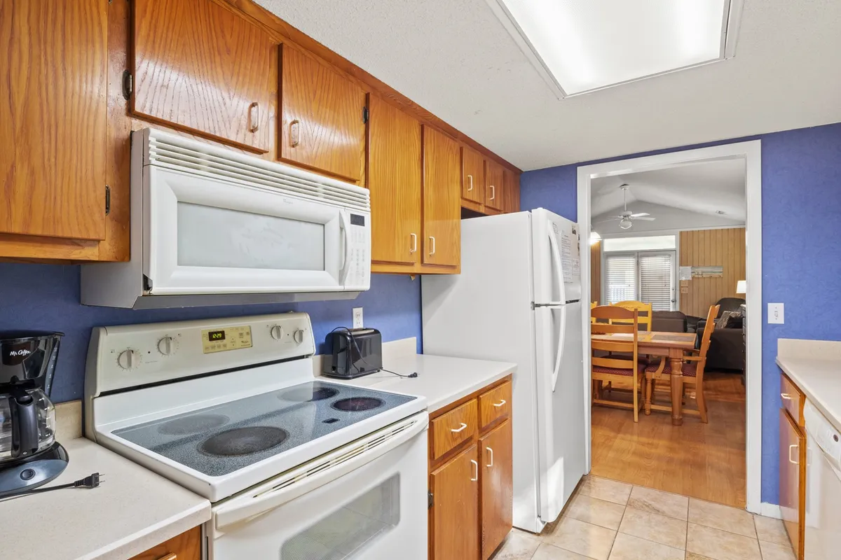 This image focuses on a well-appointed kitchen, featuring a stove, refrigerator, kitchen counter, and coffee maker. The scene hints at cooking and family gatherings, with ample space and modern amenities that suggest convenience and creativity.